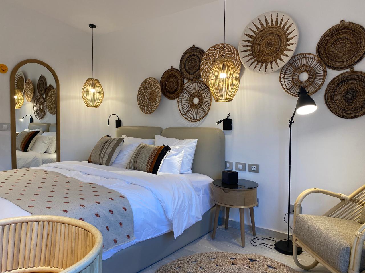 Bedroom with king bed, woven wall baskets and rattan armchair