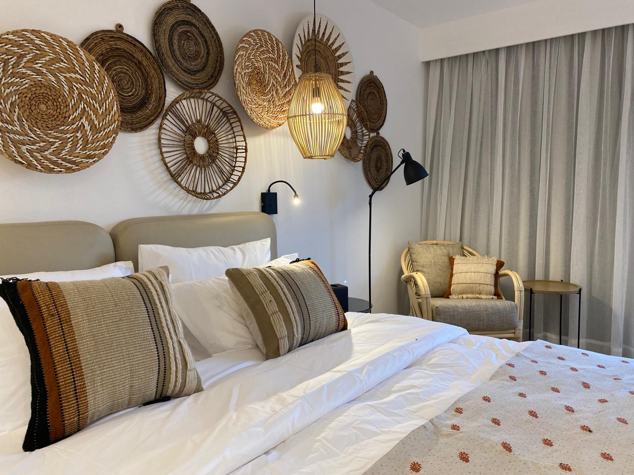 Bedroom detail with layered linens and woven wall art
